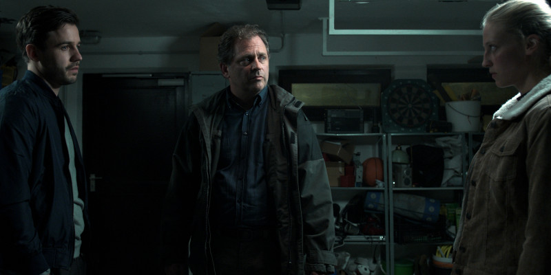 drei Personen stehen in einer Garage und sehen sich dramatisch an